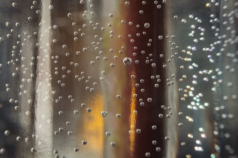 Close-up of a fizz tablet dissolving in a clear glass of water, releasing gentle bubbles.