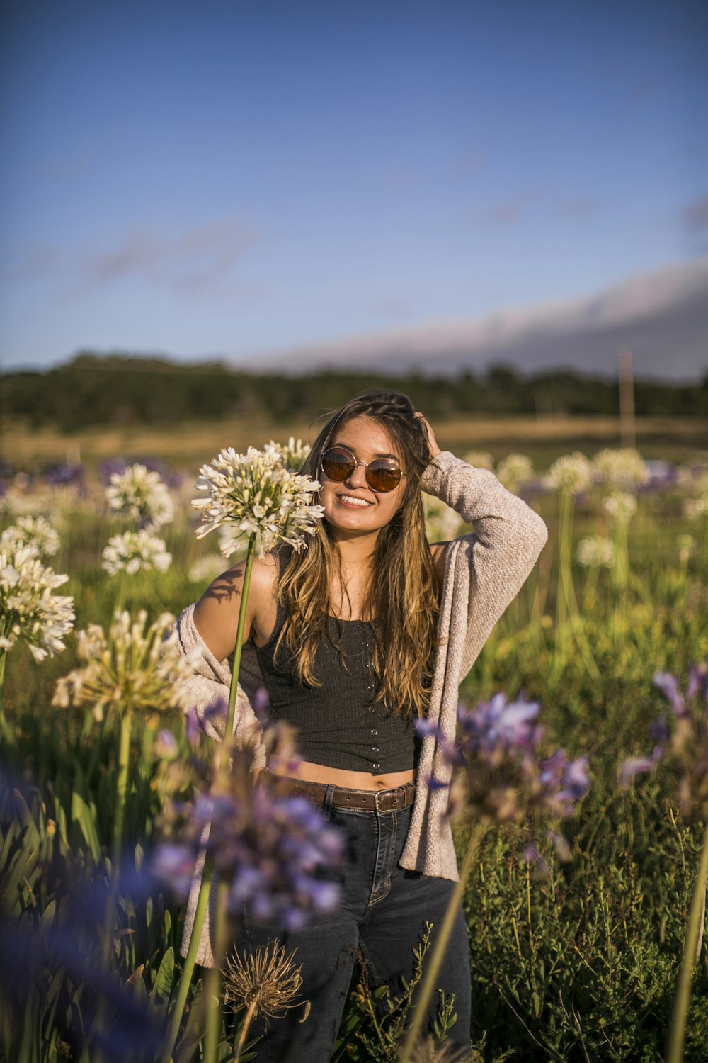 woman in black tank top and gray cardigan standing on green grass field during daytime