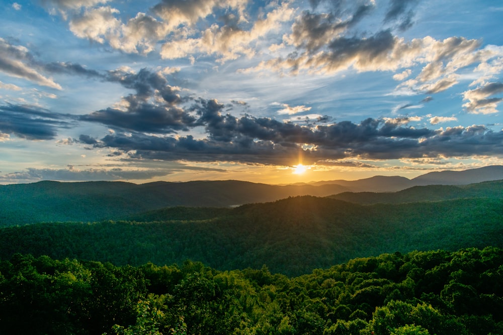 green trees and mountains during sunrise