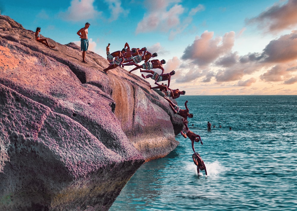 people on brown rock formation near body of water during daytime