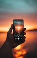 person holding black smartphone taking photo of sunset