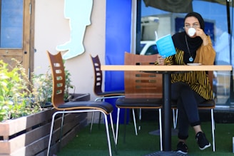 A serene outdoor scene with a woman enjoying a cup of coffee while reading a financial book.