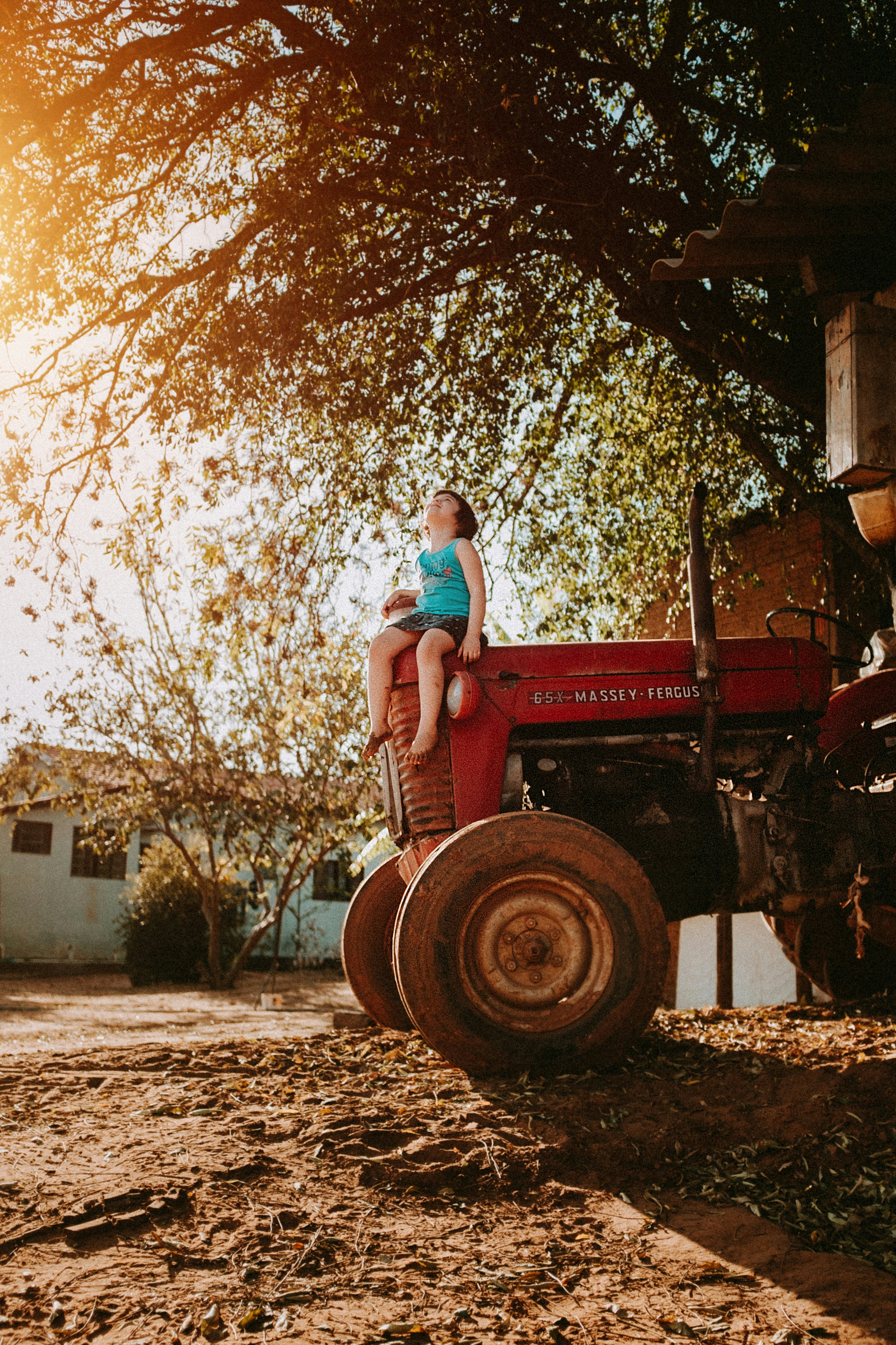 woman in blue denim jeans sitting on red tractor during daytime