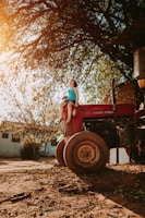 woman in blue denim jeans sitting on red tractor during daytime