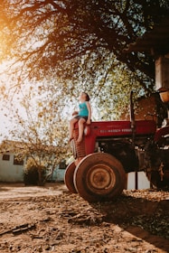 woman in blue denim jeans sitting on red tractor during daytime