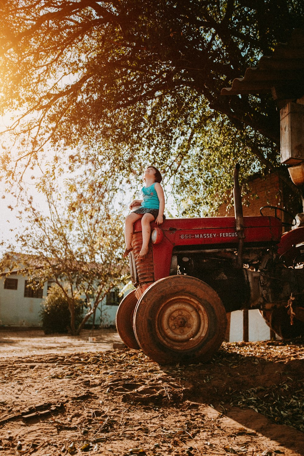 woman in blue denim jeans sitting on red tractor during daytime