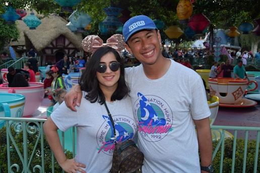 A cheerful dad and child wearing Mickey ears, smiling in front of Cinderella Castle at Disney World on a sunny day.