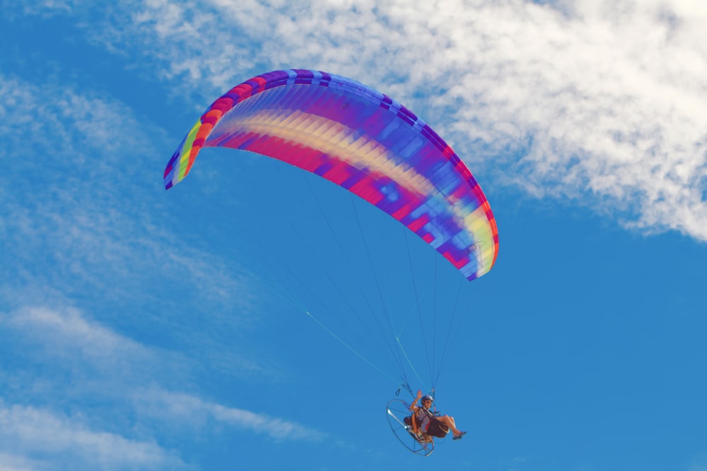 person in red and yellow parachute under blue sky during daytime