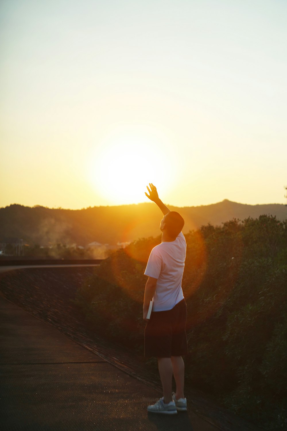 man in white t-shirt standing on dock during sunset