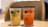 Two branded cups with black lids on a table, one containing a yellowish drink with lime and the other a reddish drink with fruit pieces.