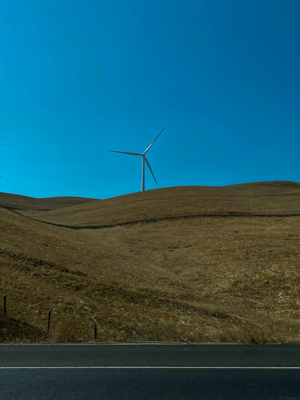 turbinas eólicas brancas na colina marrom sob o céu azul durante o dia