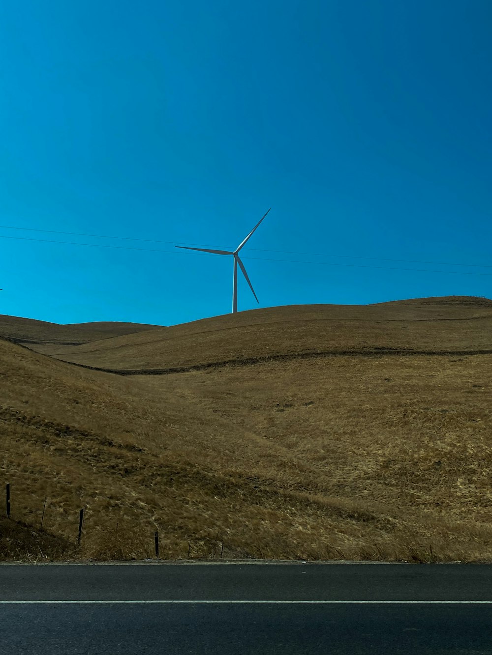 white wind turbines on brown hill under blue sky during daytime