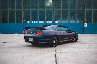 Wide-angle view of a sleek sports car with a mirror-like finish parked in front of a modern building.