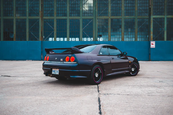 Wide-angle view of a sleek sports car with a mirror-like finish parked in front of a modern building.
