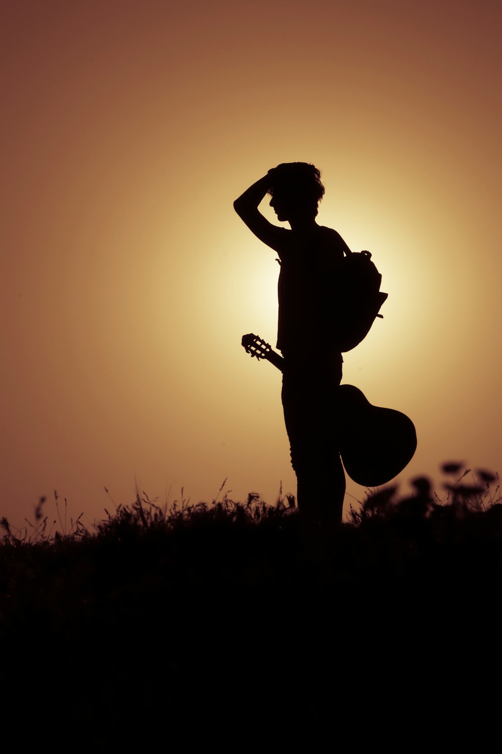silhouette of man playing guitar during sunset