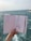 A hand holds a sketchbook open to reveal fashion illustrations against a background of the sea. The sketches depict clothing designs, including a long dress and a jumpsuit, both enhanced with detailed patterns. The ocean is visible in the distance, with slight waves under a muted sky.
