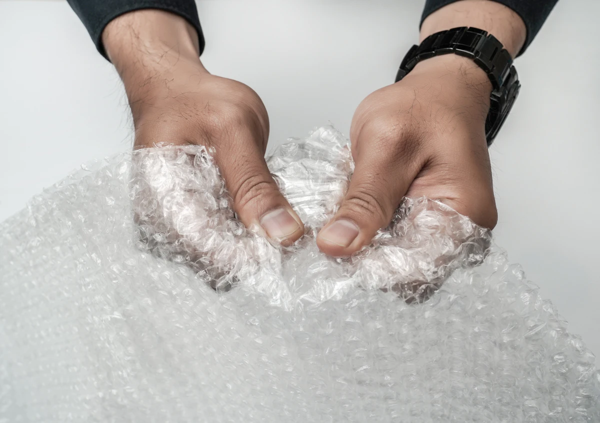 Tangan pemilik toko membungkus barang dengan pembungkus kain putih di meja packing