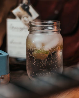 Close-up of a glass jar filled with vibrant homemade kombucha bubbling gently on a rustic wooden table.