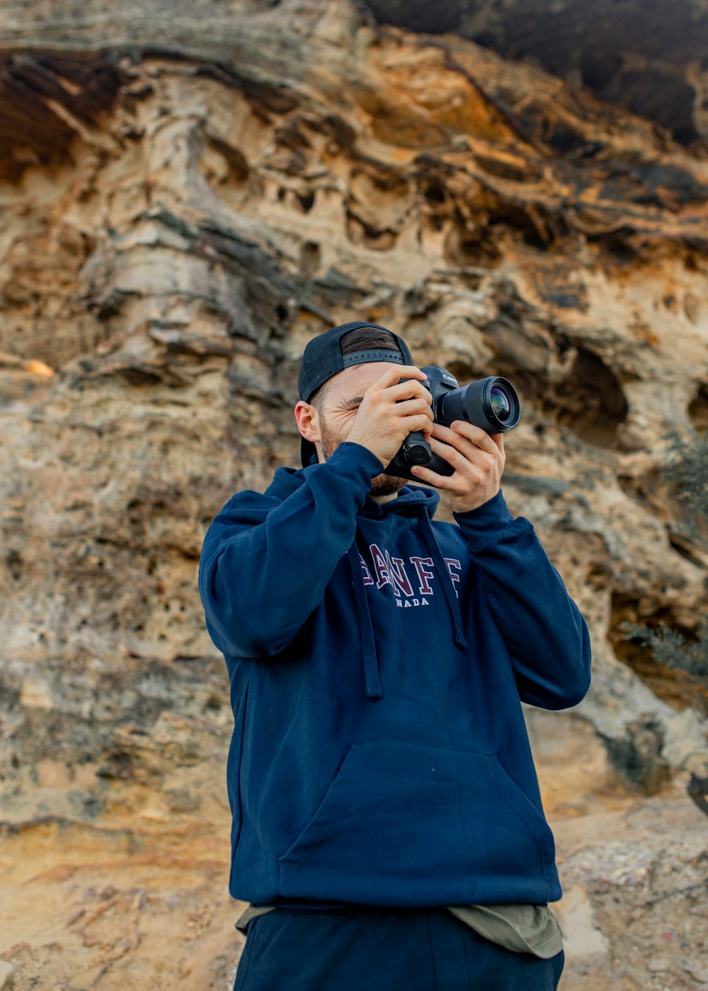 homem no capuz azul segurando a câmera dslr preta