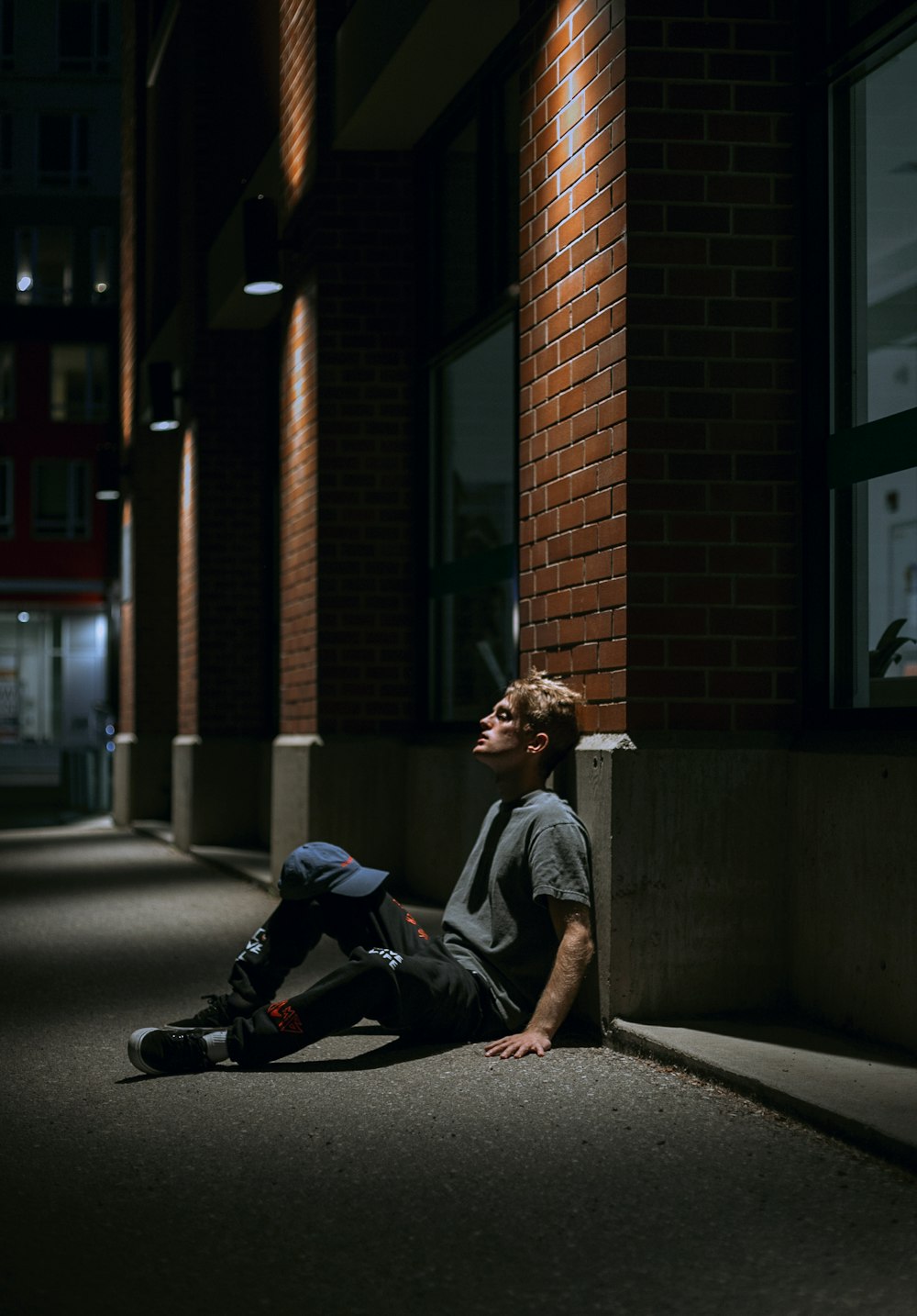 man in gray crew neck t-shirt sitting on sidewalk during daytime