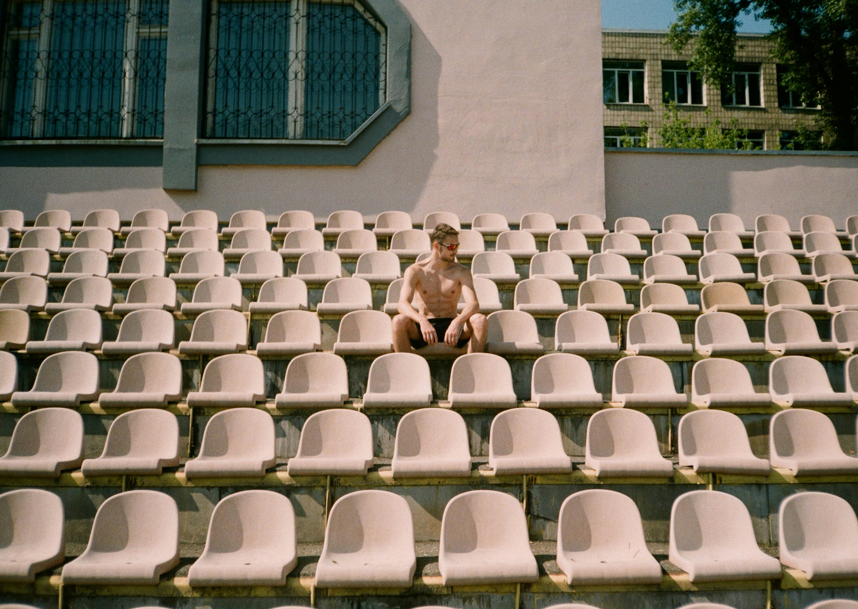 topless man sitting on white plastic chair