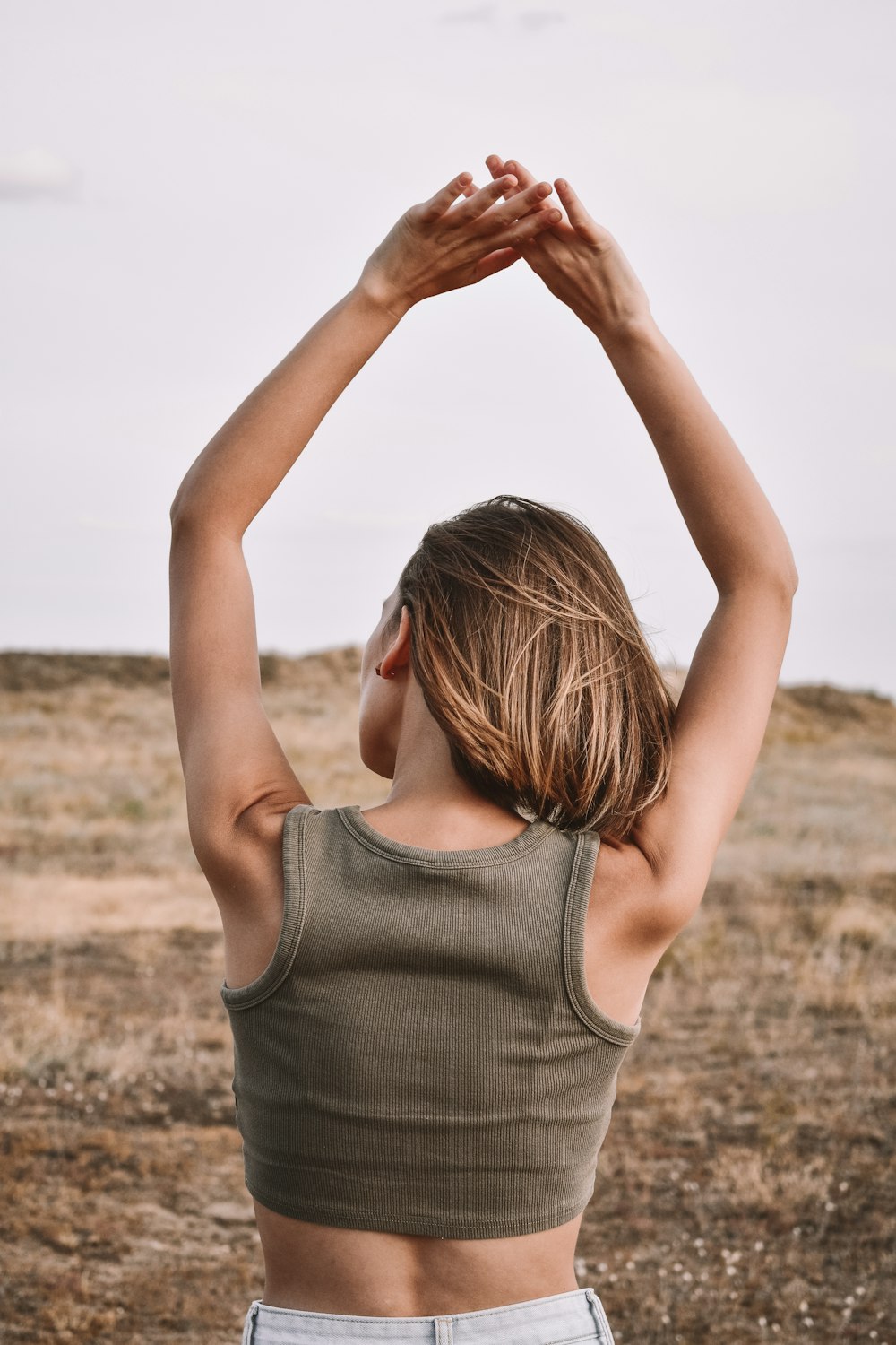 woman in gray tank top raising her hands