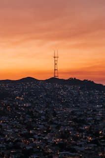 A lively radio host speaking into a microphone with a cityscape background at sunset.
