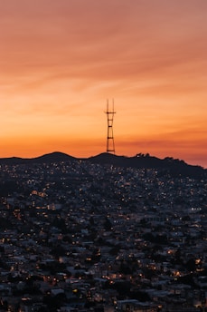 A lively radio host speaking into a microphone with a cityscape background at sunset.