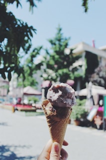 A family enjoying ice cream cones together at a sunny outdoor seating area.