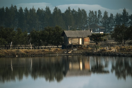 brown wooden house near lake and green trees during daytime in Aceh Besar Indonesia