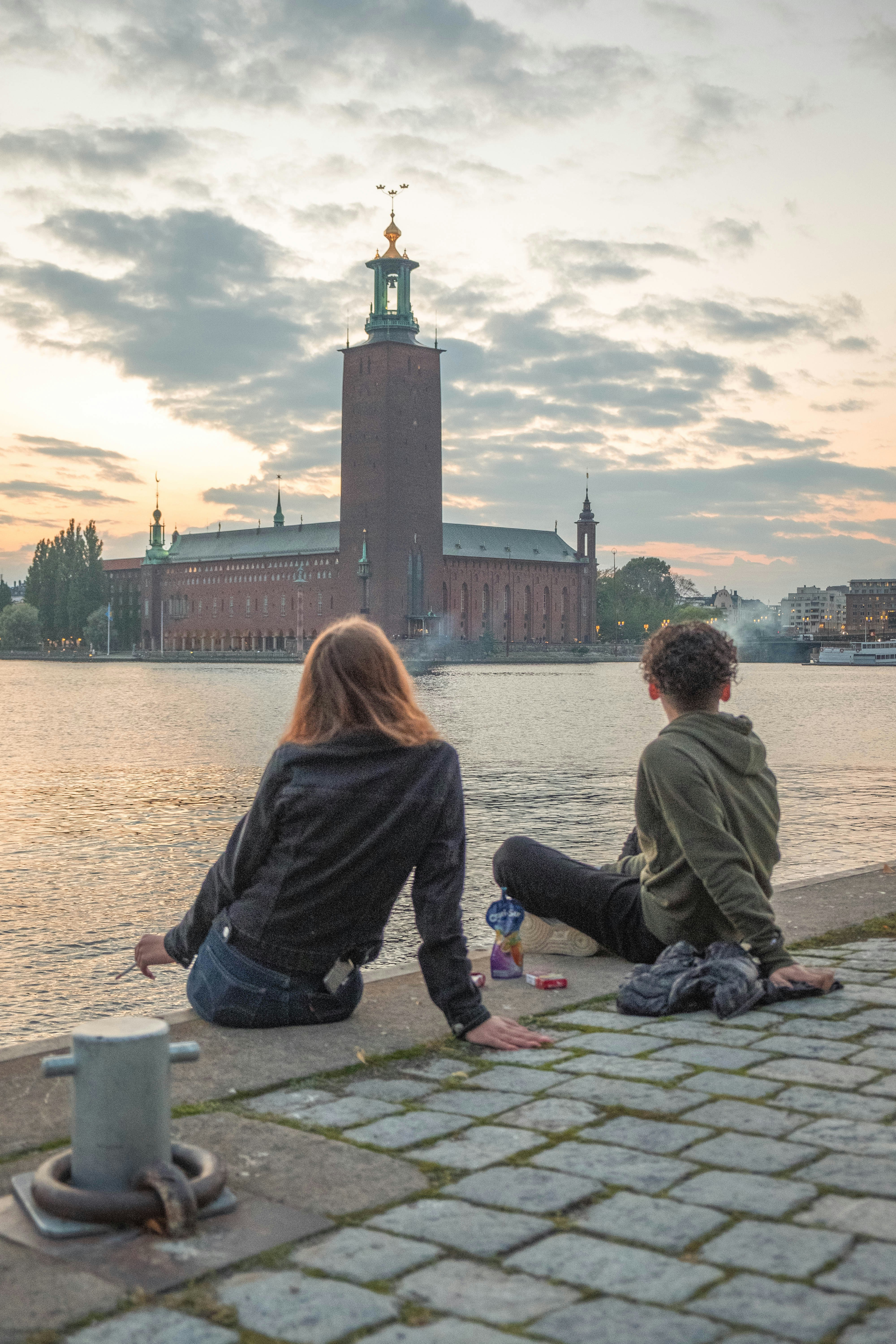 couple sitting on concrete dock during daytime