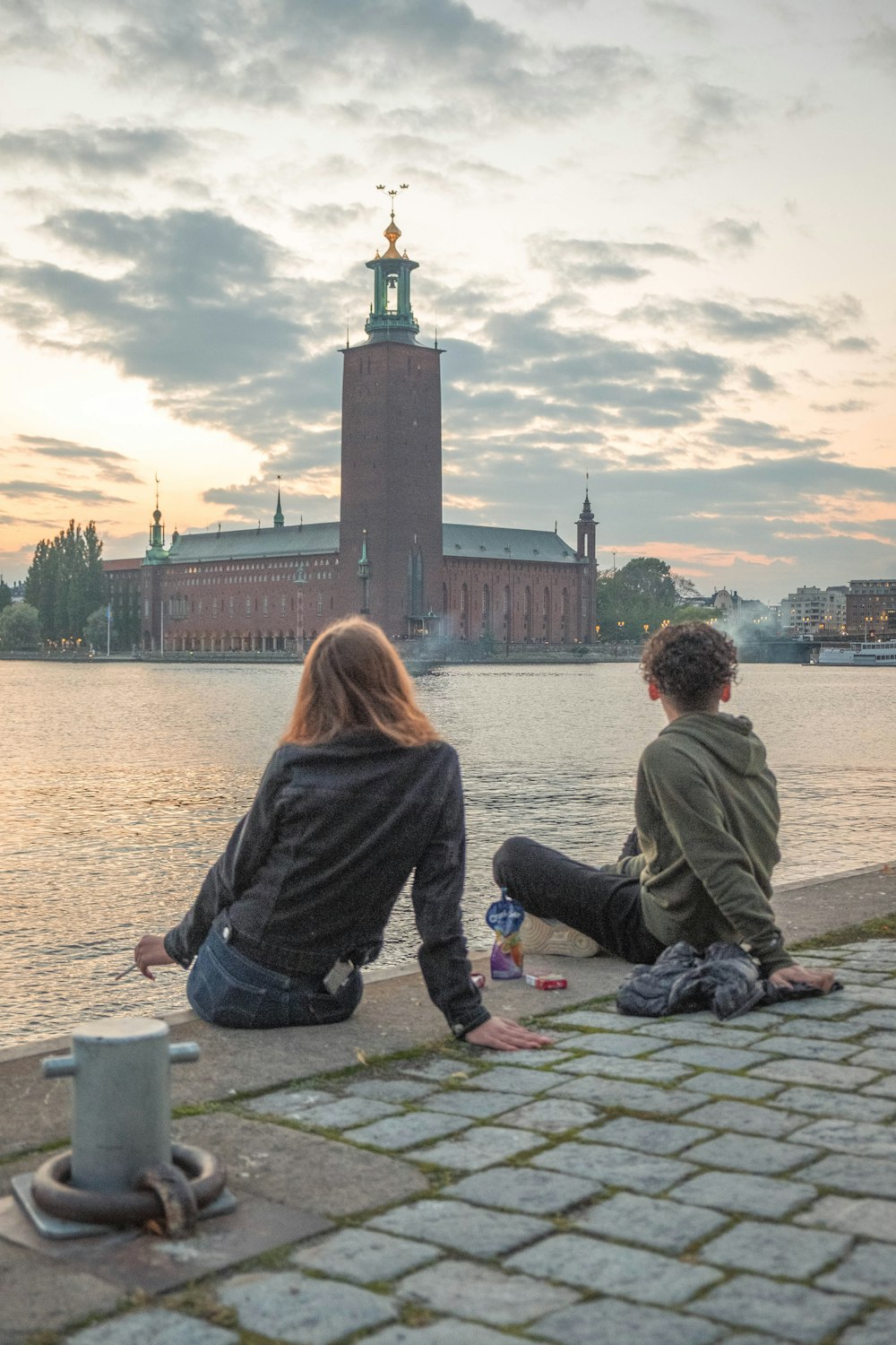 couple sitting on concrete dock during daytime