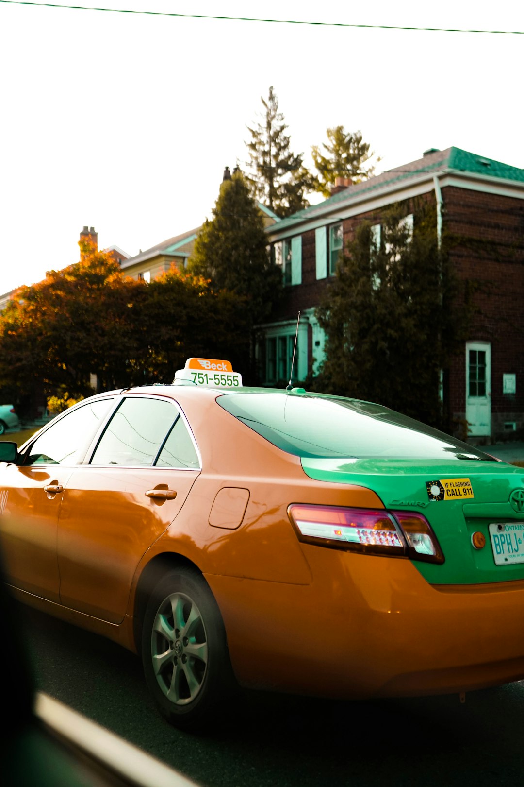 brown sedan parked near white and brown house during daytime