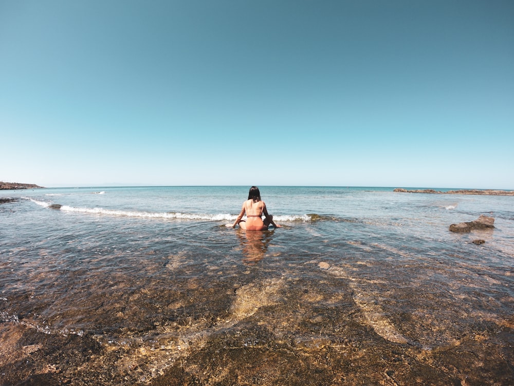 woman in black bikini lying on beach during daytime