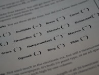 A printed page displaying different typographic symbols used as diacritical marks along with their names. Labels such as 'Circumflex', 'Macron', 'Tilde', and others are presented next to the corresponding graphical symbols. The text and symbols are organized in a structured manner across the page, combining educational content with visual representations.