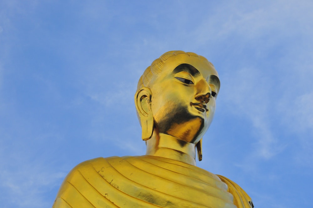 gold statue of man under blue sky during daytime