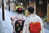 2 women in white and red floral dress walking on sidewalk during daytime