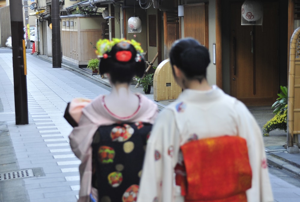 2 mulheres em vestido floral branco e vermelho andando na calçada durante o dia