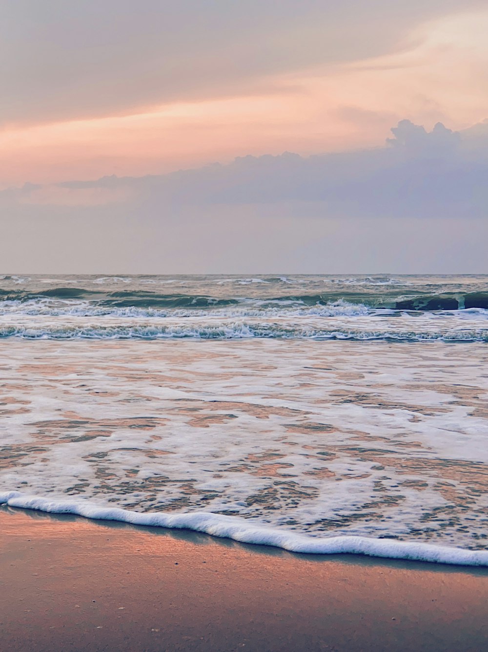 ocean waves crashing on shore during sunset