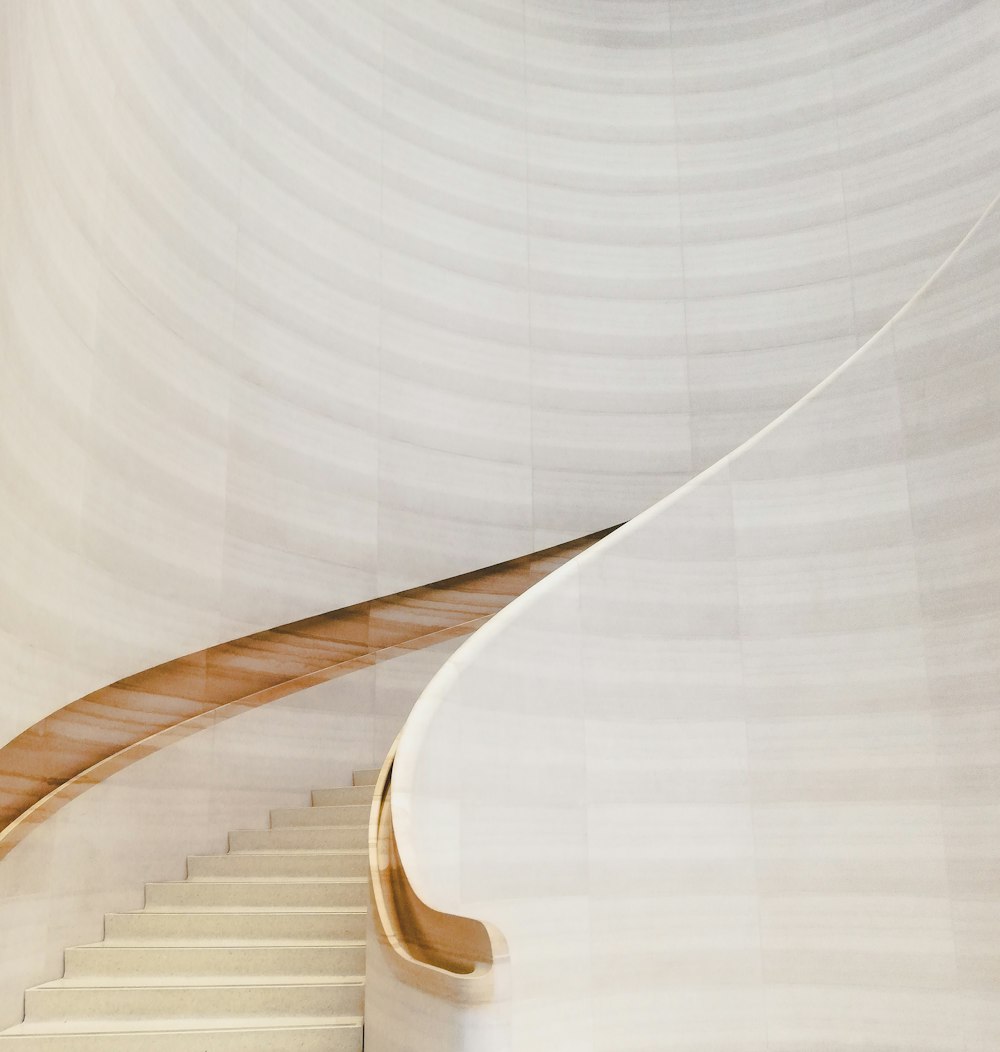 갈색 나무 난간이 있는 흰색 콘크리트 나선형 계단