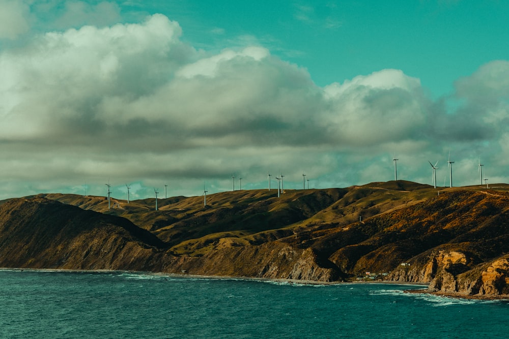 white wind turbines on brown mountain under white clouds and blue sky during daytime