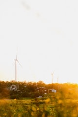 Wind turbines spinning gently over a lush landscape near eco-friendly homes.