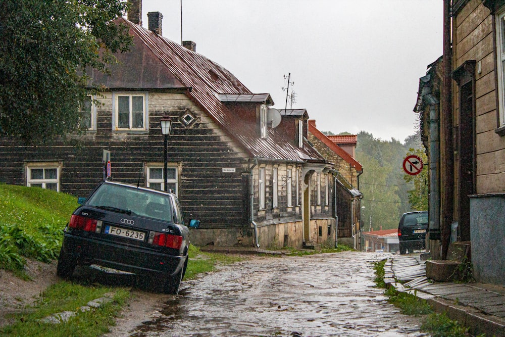 black car parked beside brown brick building during daytime