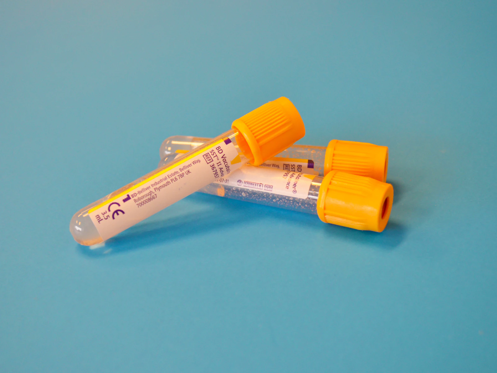 Two capped sample tubes on a blue surface