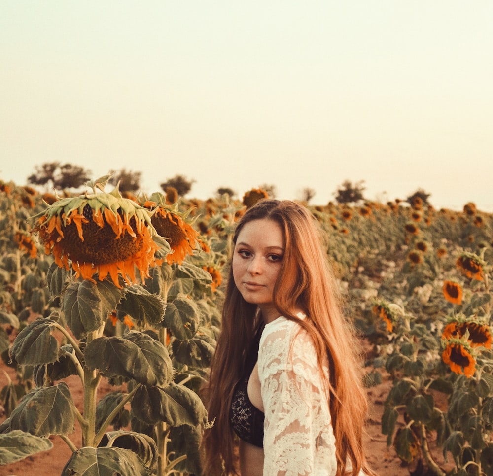 woman in white jacket standing on sunflower field during daytime