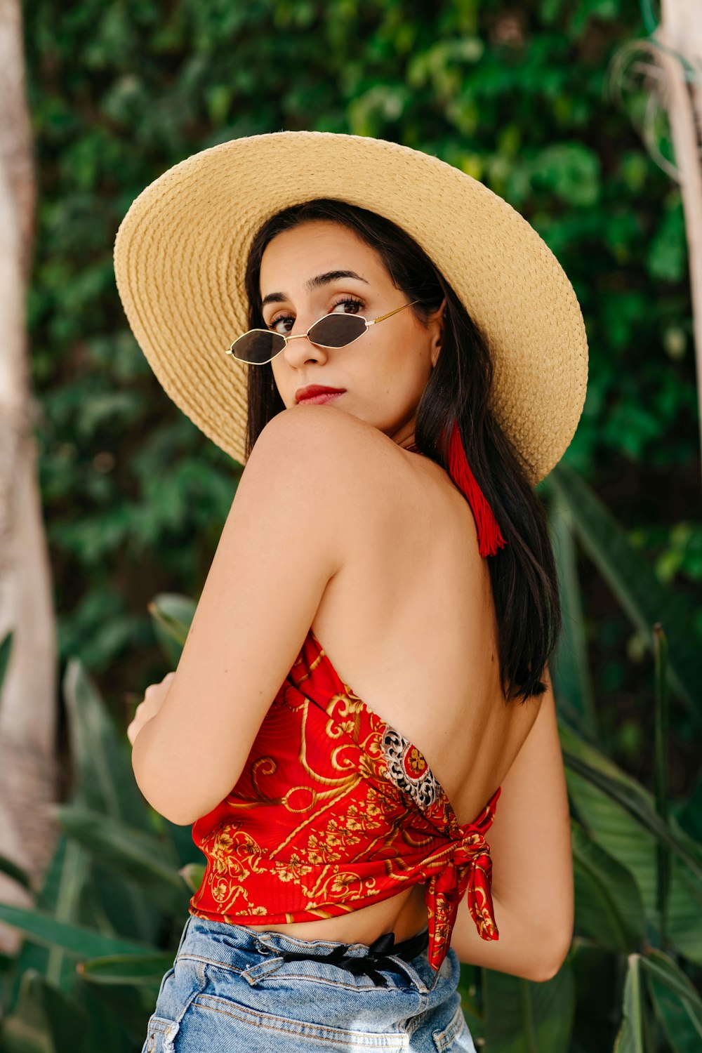 woman in red and white floral tube dress wearing brown sun hat