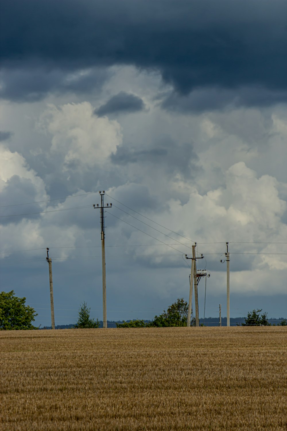 gray electric post under white clouds during daytime