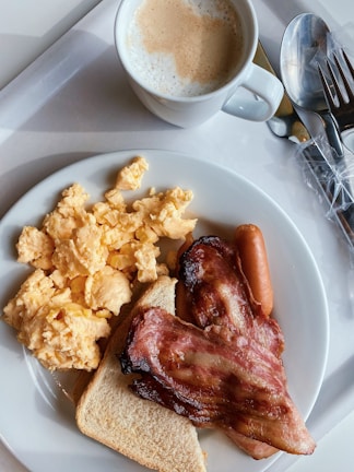 A steaming cup of rich, frothy coffee alongside a plate of golden, crispy breakfast potatoes and eggs.