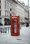 red telephone booth near white concrete building during daytime
