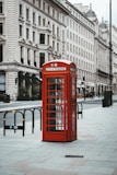 red telephone booth near white concrete building during daytime